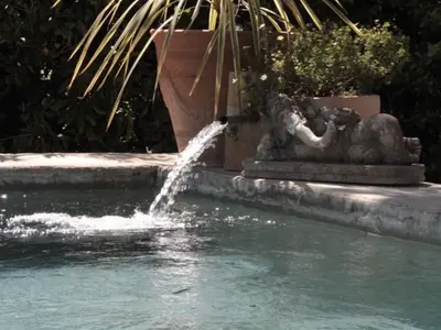 a fountain in the middle of a pool of water at Le Mas Des Bardes in Pernes-les-Fontaines