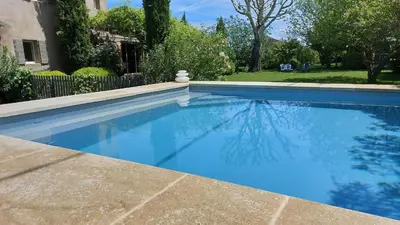 a swimming pool with blue water in a yard at Le Mas Des Bardes in Pernes-les-Fontaines