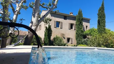 a swimming pool in front of a house at Le Mas Des Bardes in Pernes-les-Fontaines