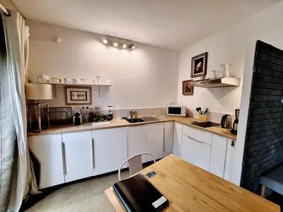 a kitchen with white cabinets and a wooden table at Le Mas Des Bardes in Pernes-les-Fontaines