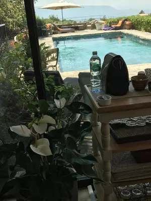 a bottle of water sitting on a table next to a swimming pool at La Borie en Provence in Gordes