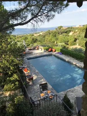 a swimming pool with a table and chairs next to it at La Borie en Provence in Gordes