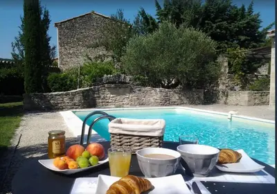 a table with bread and fruit next to a swimming pool at Le Petit Bastidon - Private pool - Gordes in Gordes