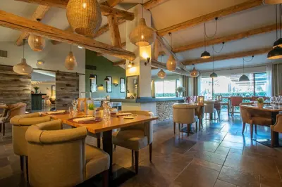 a restaurant with wooden tables and chairs in a room at Domaine la Pierre Blanche in Eygalières