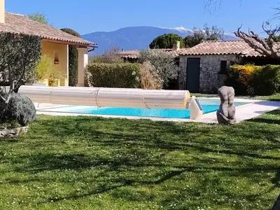 a green chair next to a table next to a pool at Petit gite de Provence in Mazan