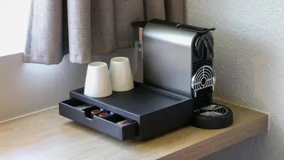 a black hair dryer sitting on a shelf with towels at Campanile Prime - Aix-en-Provence Sud - Pont de l'Arc in Aix-en-Provence