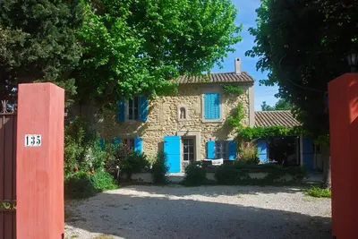 an old stone house with blue doors and trees at Les Volets Bleus Provence in Salon-de-Provence