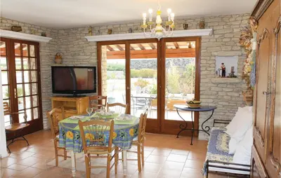 a dining room with a table and a television at 3 Bedroom Stunning Home In Gordes in Gordes