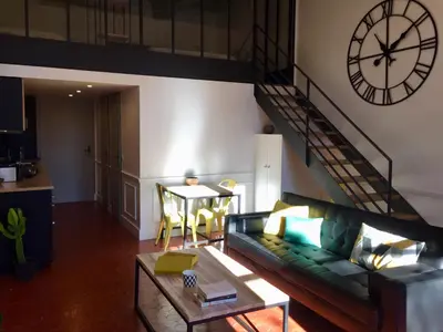 a living room with a couch and a clock on the wall at Les Suites du Cours & Spa in Aix-en-Provence