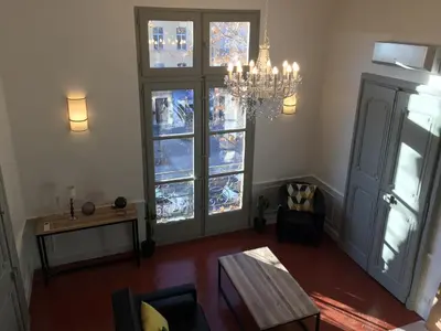 a living room with a chandelier and two large windows at Les Suites du Cours & Spa in Aix-en-Provence
