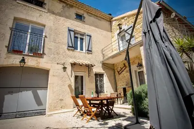 a patio with a table and an umbrella in front of a house at La Maison du Moulin de Tartay in Avignon