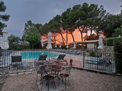 a table and chairs with umbrellas next to a pool at Hôtel Restaurant Mas de Fauchon - Teritoria in Saint-Cannat