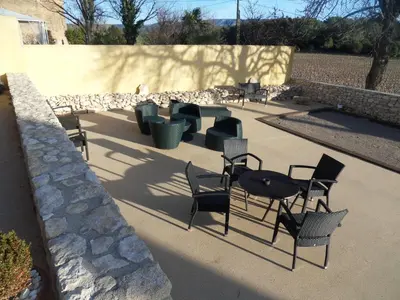 a patio with chairs and tables and a stone wall at Domaine de L'Olibaou in Venelles