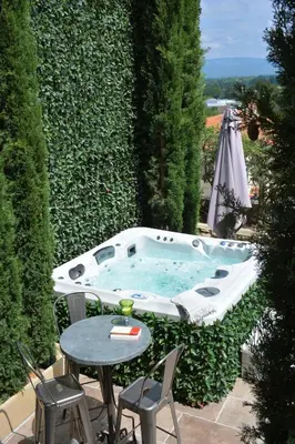 a hot tub on a patio with a table and chairs at Le Petit Chateau in Châteauneuf-de-Gadagne