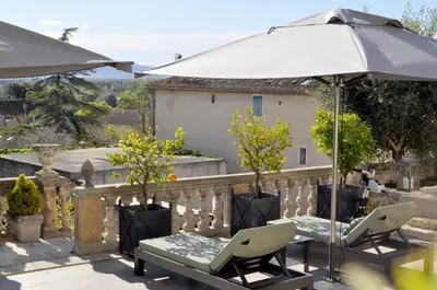 a patio with two chairs and an umbrella at Le Petit Chateau in Châteauneuf-de-Gadagne