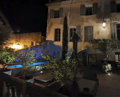 a building at night with tables and trees in front at Le Petit Chateau in Châteauneuf-de-Gadagne