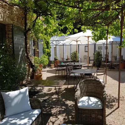 an outdoor patio with tables and chairs and umbrellas at Le Mas Vigneron in Gordes