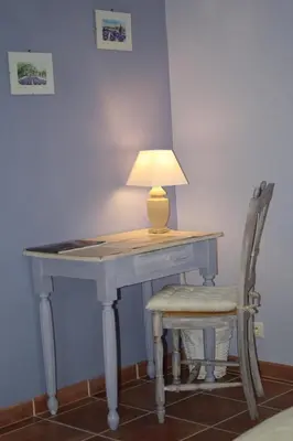 a desk with a lamp and a chair next to it at Le Mas Vigneron in Gordes