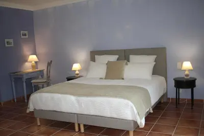 a bedroom with a large bed with white sheets and pillows at Le Mas Vigneron in Gordes