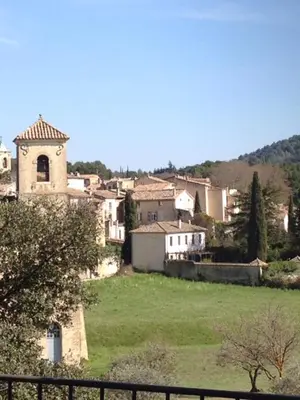 a small village with a church and a green field at La Calade in Lourmarin