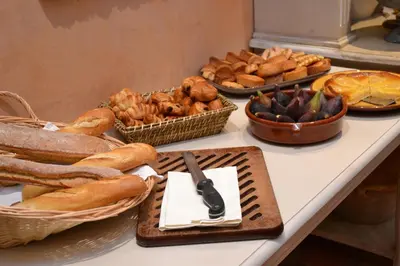 a table topped with baskets of bread and pastries at Hotel du Poète in Fontaine-de-Vaucluse