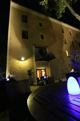 a building with a table and chairs at night at Hotel du Poète in Fontaine-de-Vaucluse