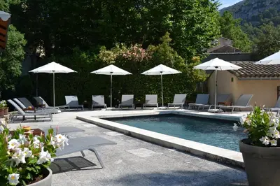 a swimming pool with chairs and umbrellas at Hotel du Poète in Fontaine-de-Vaucluse