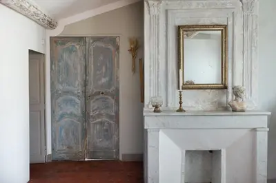 a room with a fireplace and a mirror on a door at La Madone in Apt