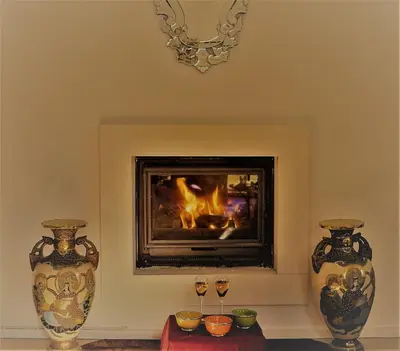 a fireplace with two vases and two glasses on a table at Les Jardins d'Eleusis in Murs