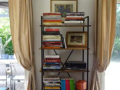 a book shelf filled with books next to a window at Les Jardins d'Eleusis in Murs