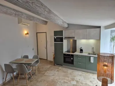 a kitchen with green cabinets and a table and chairs at Nuit Etoilée in LʼIsle-sur-la-Sorgue