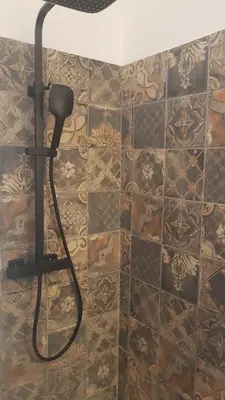 a shower head in a bathroom with a tiled wall at La Maison de Charlie in Vaugines