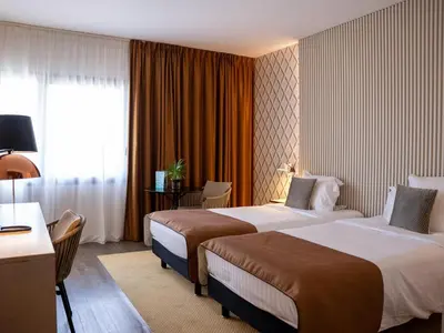 a hotel room with two beds and a window at Aquabella Hôtel & Spa in Aix-en-Provence