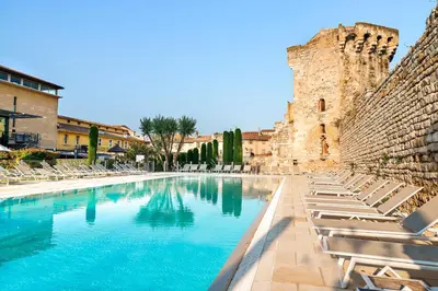 a swimming pool with lounge chairs and a castle at Aquabella Hôtel & Spa in Aix-en-Provence