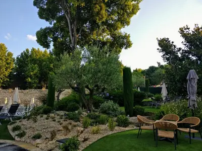a garden with a table and chairs and a tree at Aquabella Hôtel & Spa in Aix-en-Provence