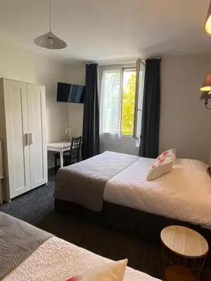 a bedroom with two beds and a desk and a window at Grand Hôtel De La Poste in Salon-de-Provence