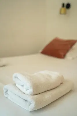 a stack of white towels sitting on a bed at Hôtel d'Angleterre, Salon-de-Provence in Salon-de-Provence