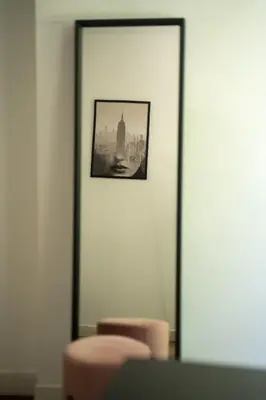 a mirror in a room with two pink stools at Hôtel d'Angleterre, Salon-de-Provence in Salon-de-Provence