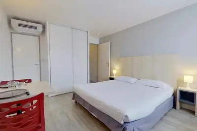 a bedroom with a large white bed and a desk at City Résidence Aix-en-Provence in Aix-en-Provence