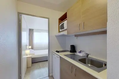 a small kitchen with a sink and a bedroom at City Résidence Aix-en-Provence in Aix-en-Provence
