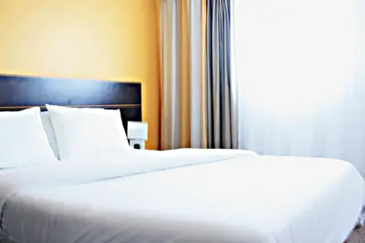 two white beds in a hotel room with a window at City Résidence Aix-en-Provence in Aix-en-Provence