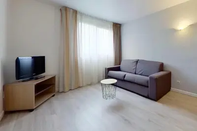 a living room with a couch and a tv at City Résidence Aix-en-Provence in Aix-en-Provence