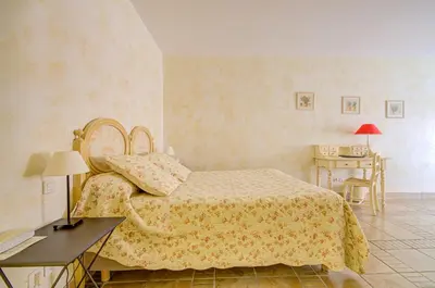 a bedroom with a bed and a desk and a table with a lamp at Omma in Roussillon