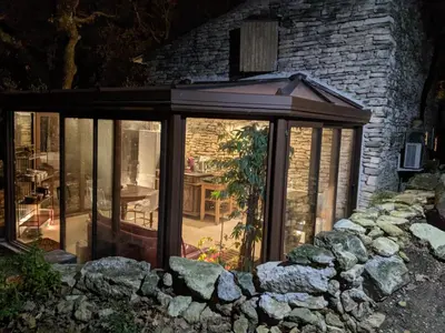 a glass greenhouse in front of a brick building at Les Rapieres Mireio in Gordes