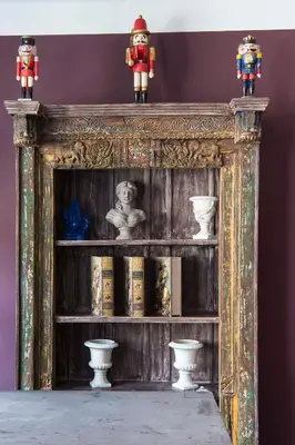 a wooden shelf with books and figurines on top of it at Un Ryad a l'Isle in LʼIsle-sur-la-Sorgue