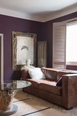 a living room with a brown leather couch and a painting at Un Ryad a l'Isle in LʼIsle-sur-la-Sorgue