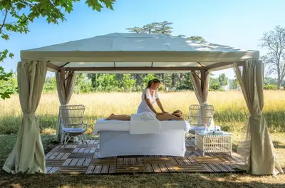a woman sitting on a bed under a gazebo at Château de Fonscolombe - Relais & Châteaux in Le Puy-Sainte-Réparade
