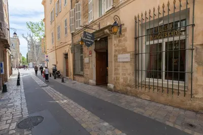 a street with people walking down a cobblestone street at Hôtel des Augustins in Aix-en-Provence
