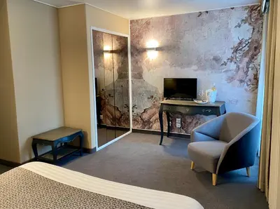 a room with a bed and a chair and a desk at Hôtel des Augustins in Aix-en-Provence