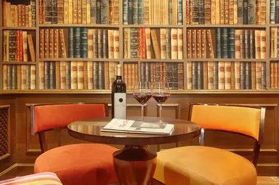 a table with two glasses of wine in front of a book shelf at Hôtel des Augustins in Aix-en-Provence